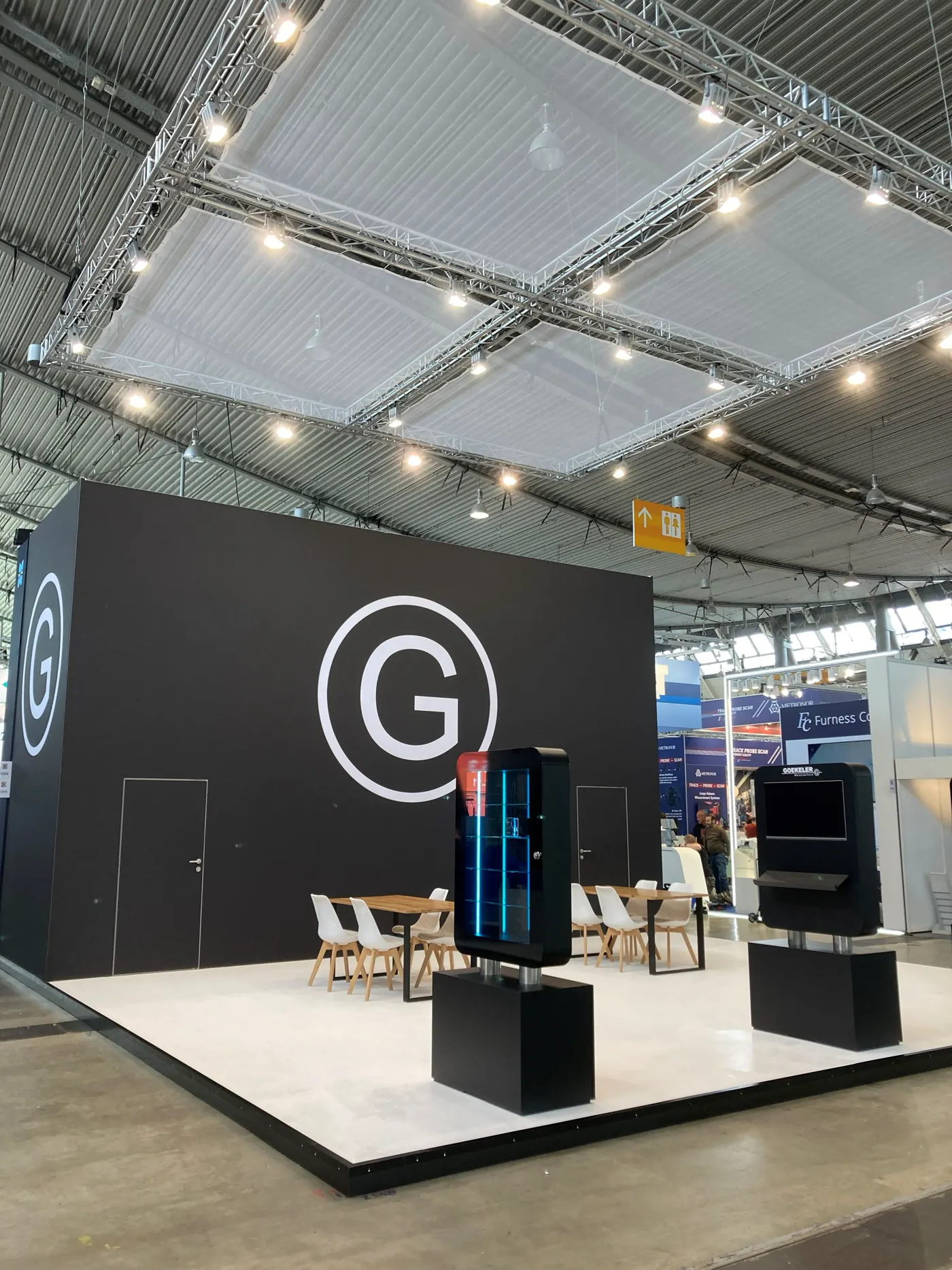 Messestand von Goekeler Messtechnik auf der Control in Stuttgart: schwarzer Kubus mit großem G-Logo, weißer Boden, Exponate und Deckensegel