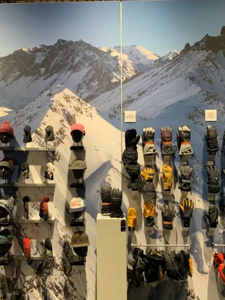 Warenwand mit Mützen und Handschuhen vor einem Bergpanorama