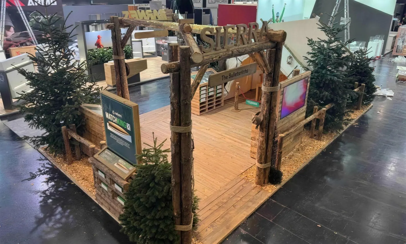 Messestand von Sierra Bullets mit Tor aus Baumstämmen, Holzboden und Tannen