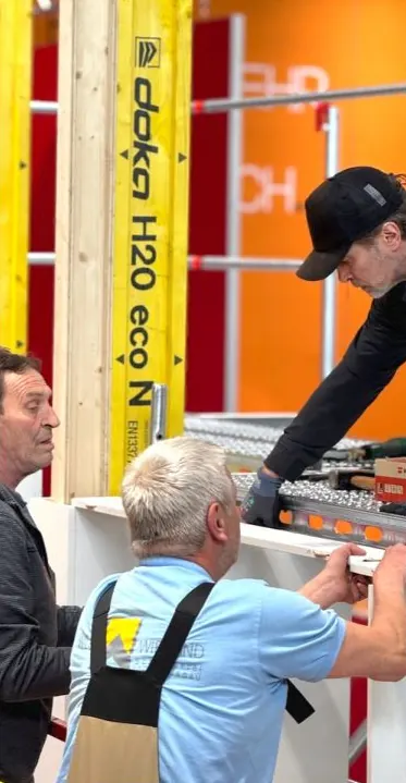 Drei Monteure richten beim Aufbau ein Bauteil aus