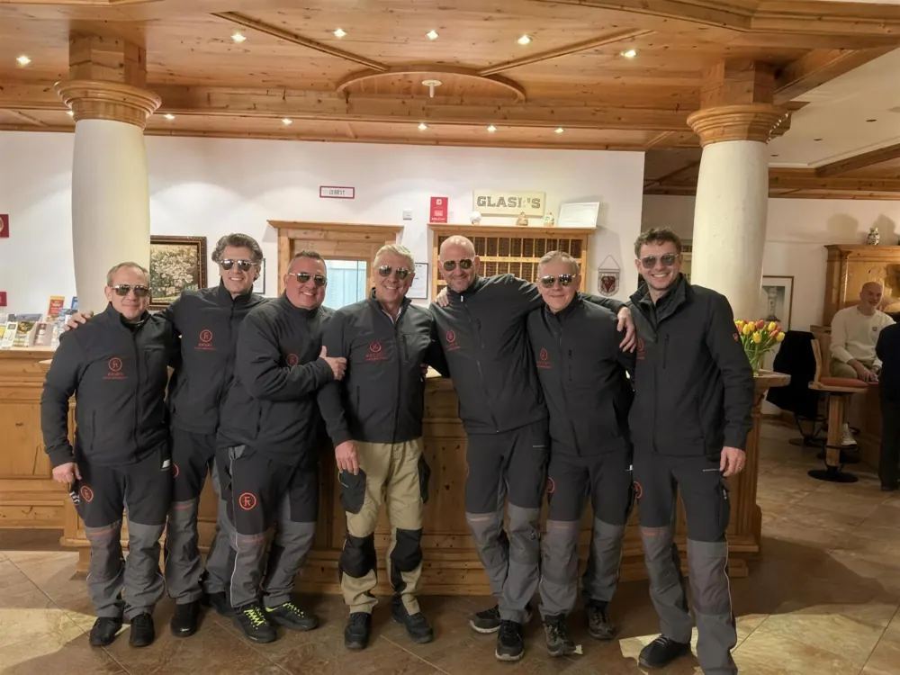 Seven FREUNDE Messebau colleagues in workwear in a hotel lobby