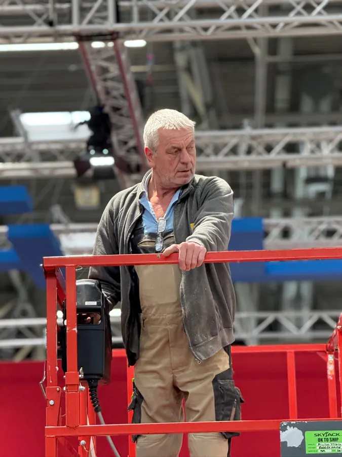 A fitter standing on a lift platform beneath a truss